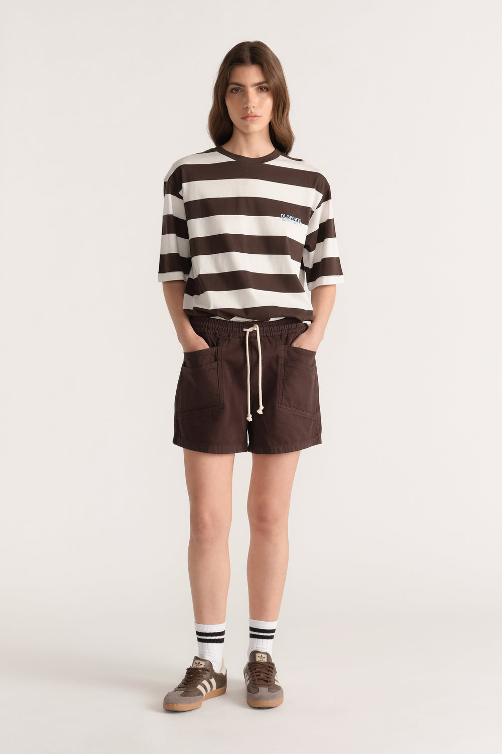Woman wearing a relaxed brown and white striped tee with drawstring shorts and sneakers