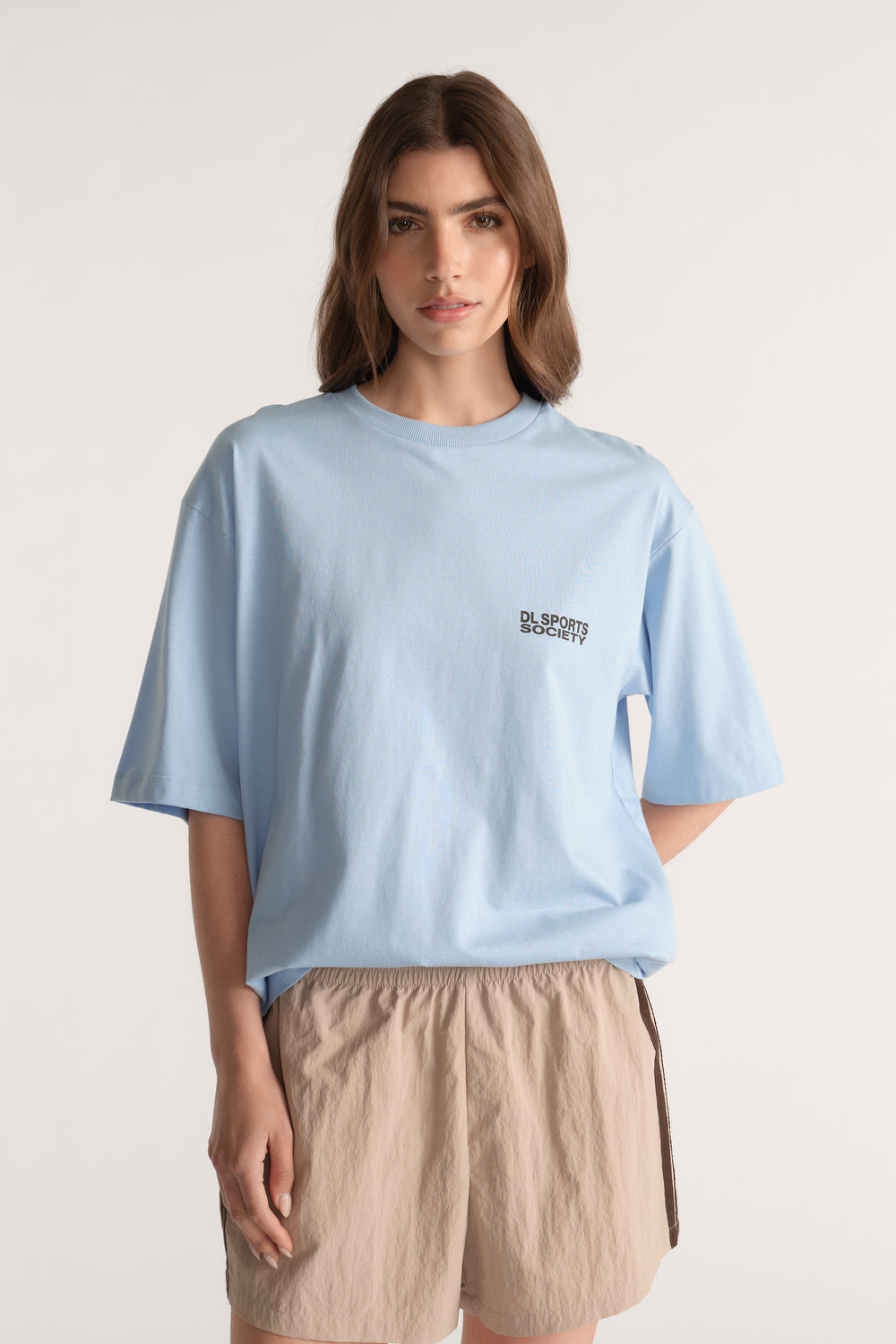 Woman wearing a relaxed light blue logo tee with beige elastic waist shorts