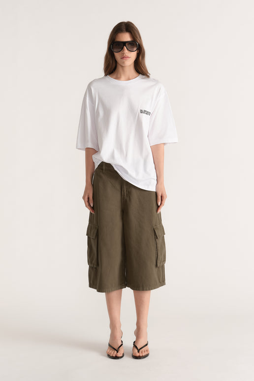 Woman wearing a white relaxed fit graphic tee with olive cargo shorts, sunglasses and black thong sandals