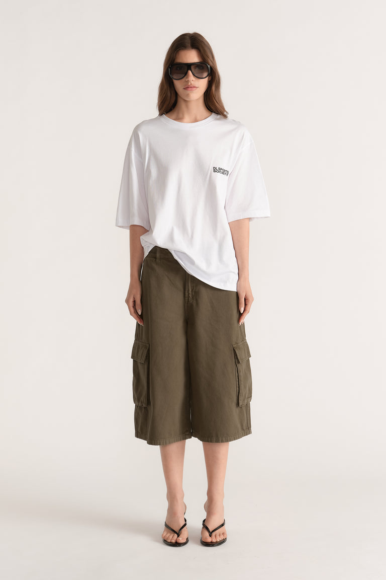 Woman wearing a white relaxed fit graphic tee with olive cargo shorts, sunglasses and black thong sandals