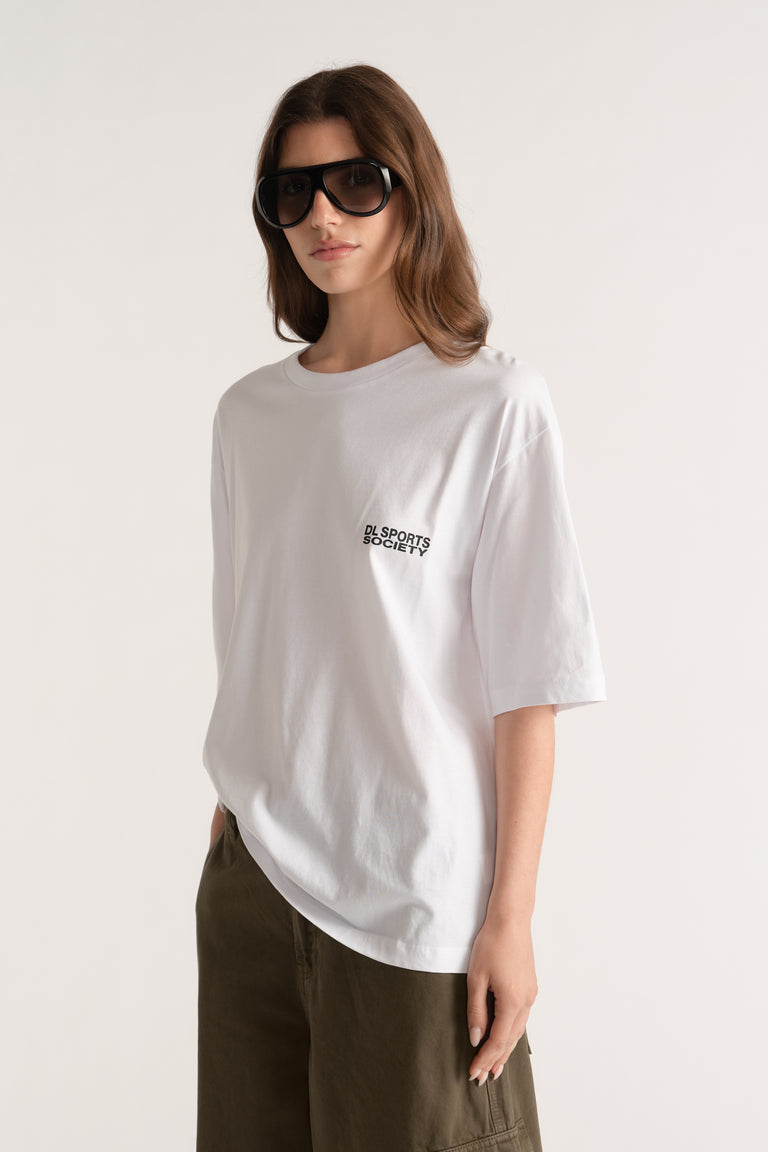 Woman wearing a white relaxed fit graphic tee with olive trousers and oversized black sunglasses