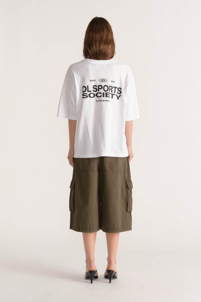 Model wearing a relaxed white graphic tee with olive cargo shorts and black heeled sandals viewed from behind