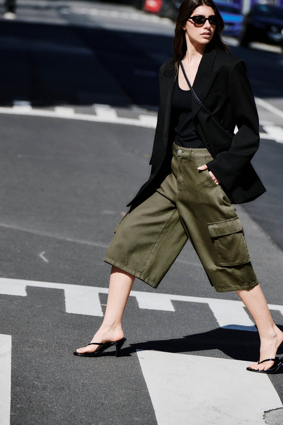 Woman wearing olive wide-leg cargo shorts with a black blazer and strappy sandals