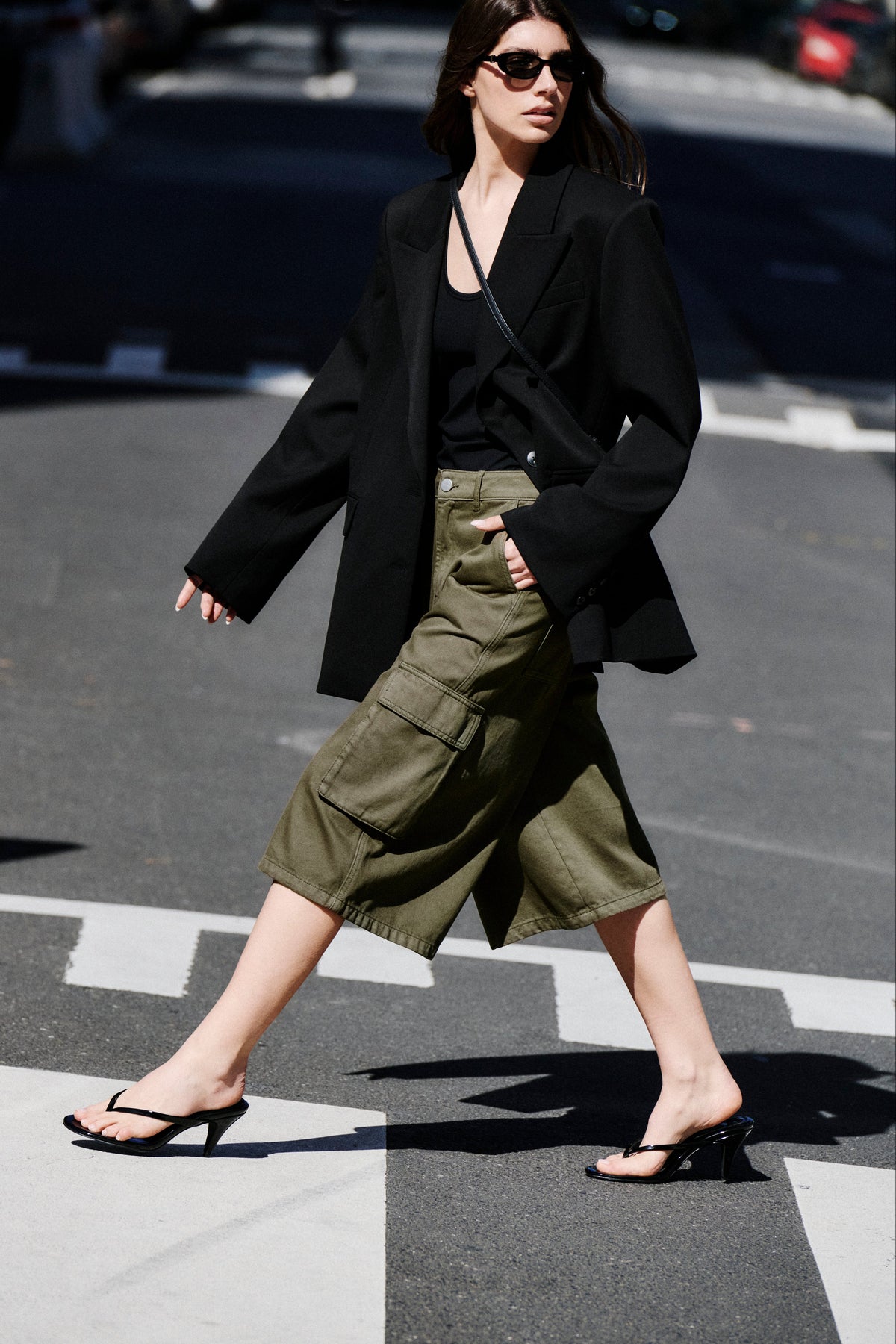 Woman wearing a black blazer with olive cargo shorts and flat sandals