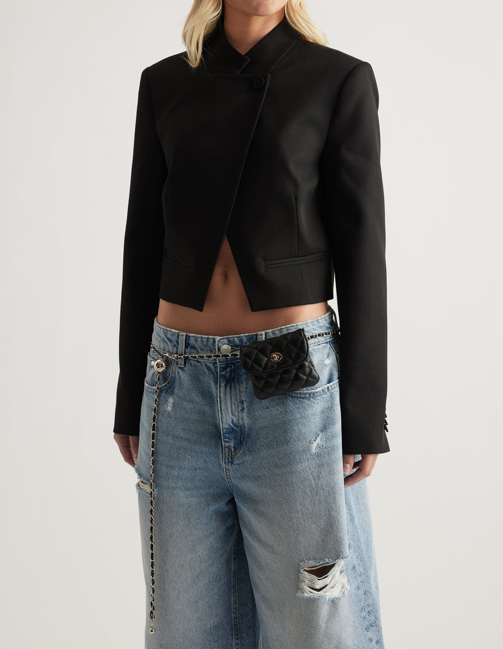 Black quilted mini bag belt with gold hardware styled over relaxed ripped jeans and a cropped black blazer