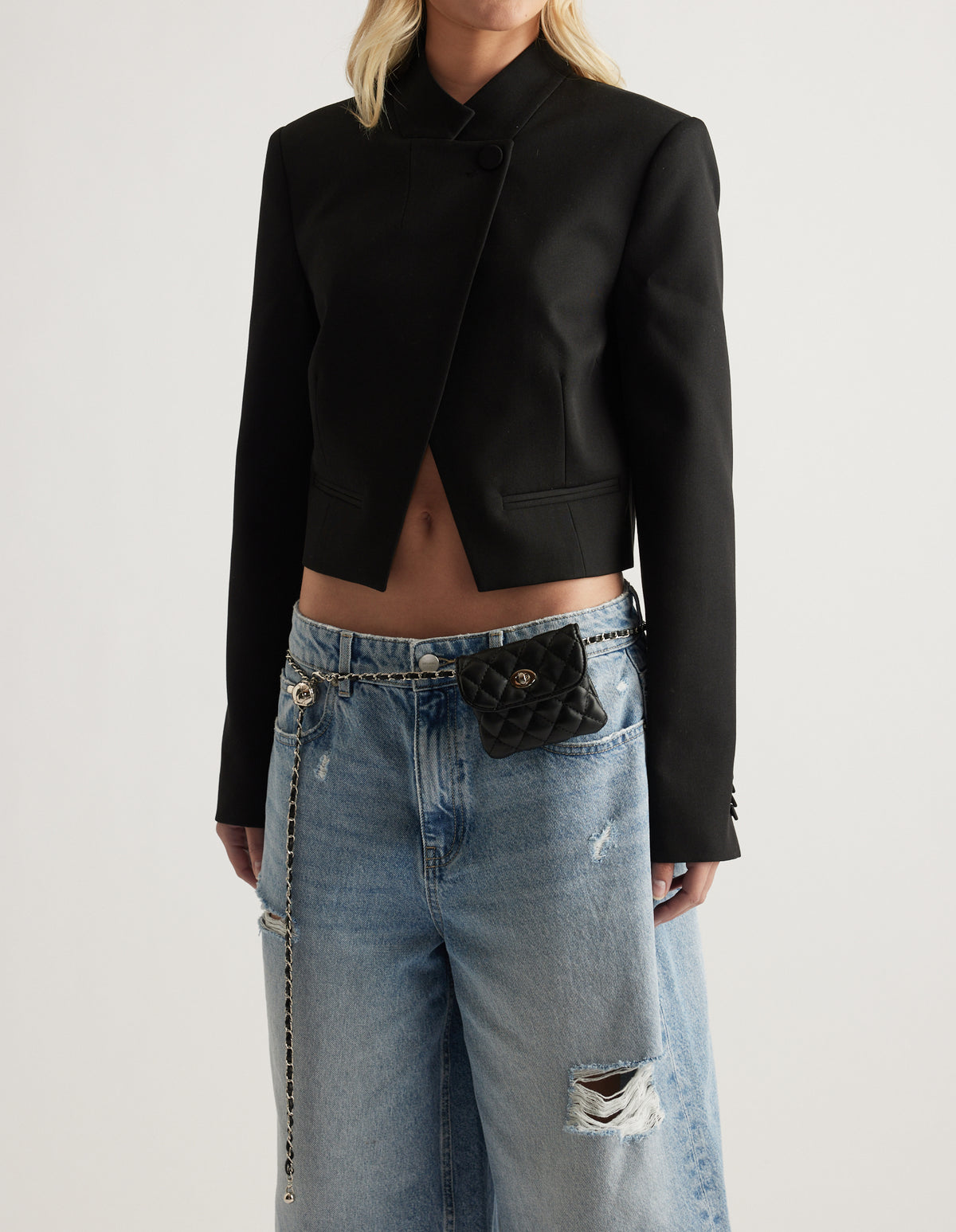Black quilted mini bag belt with gold hardware styled over relaxed ripped jeans and a cropped black blazer