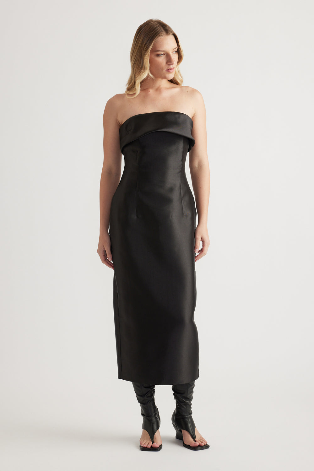 Woman wearing a black strapless fitted midi dress with a folded neckline and structured finish