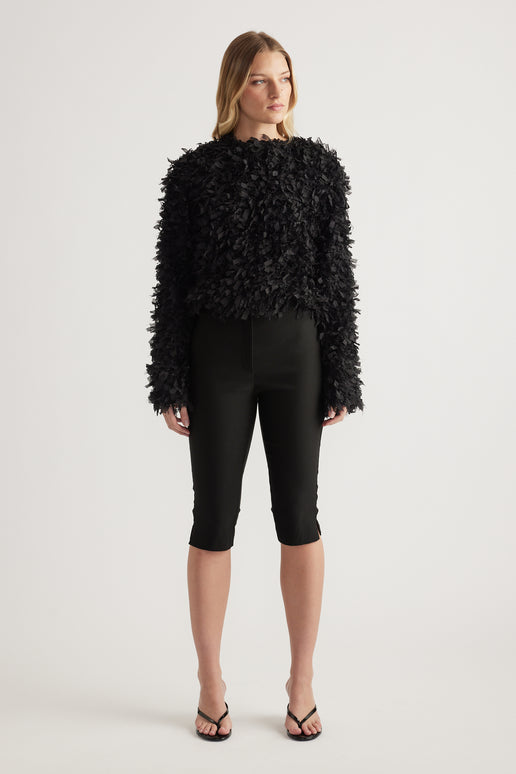 Model wearing a black textured jacket with long sleeves a round neckline and cropped hem