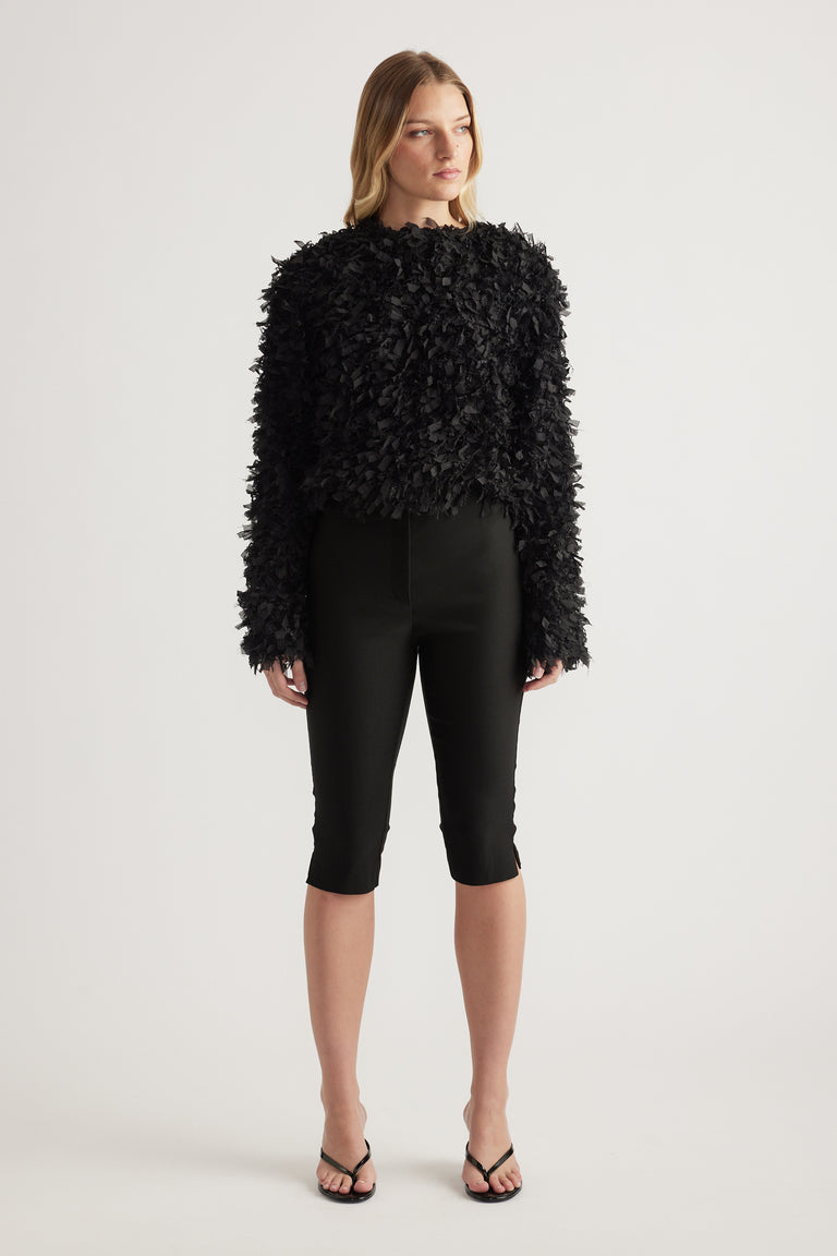 Model wearing a black textured jacket with long sleeves a round neckline and cropped hem