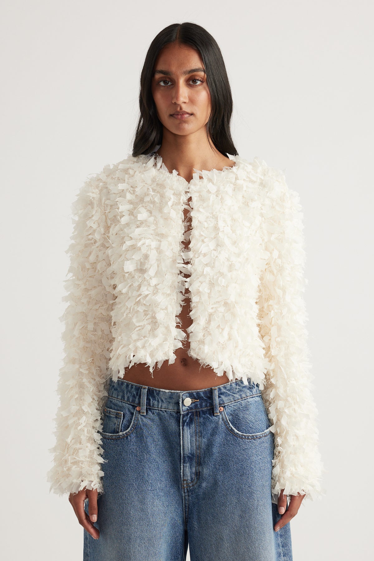 Woman wearing a cream textured jacket with long sleeves and blue jeans