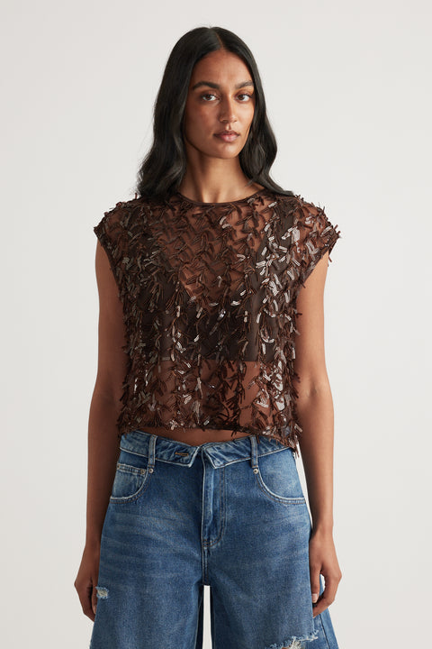 Woman wearing a brown sheer sequin cropped top with blue jeans