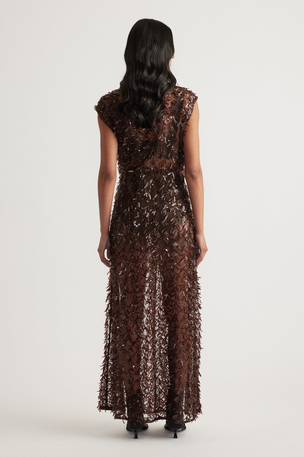 Back view of a woman wearing a brown sequin maxi skirt with a matching top