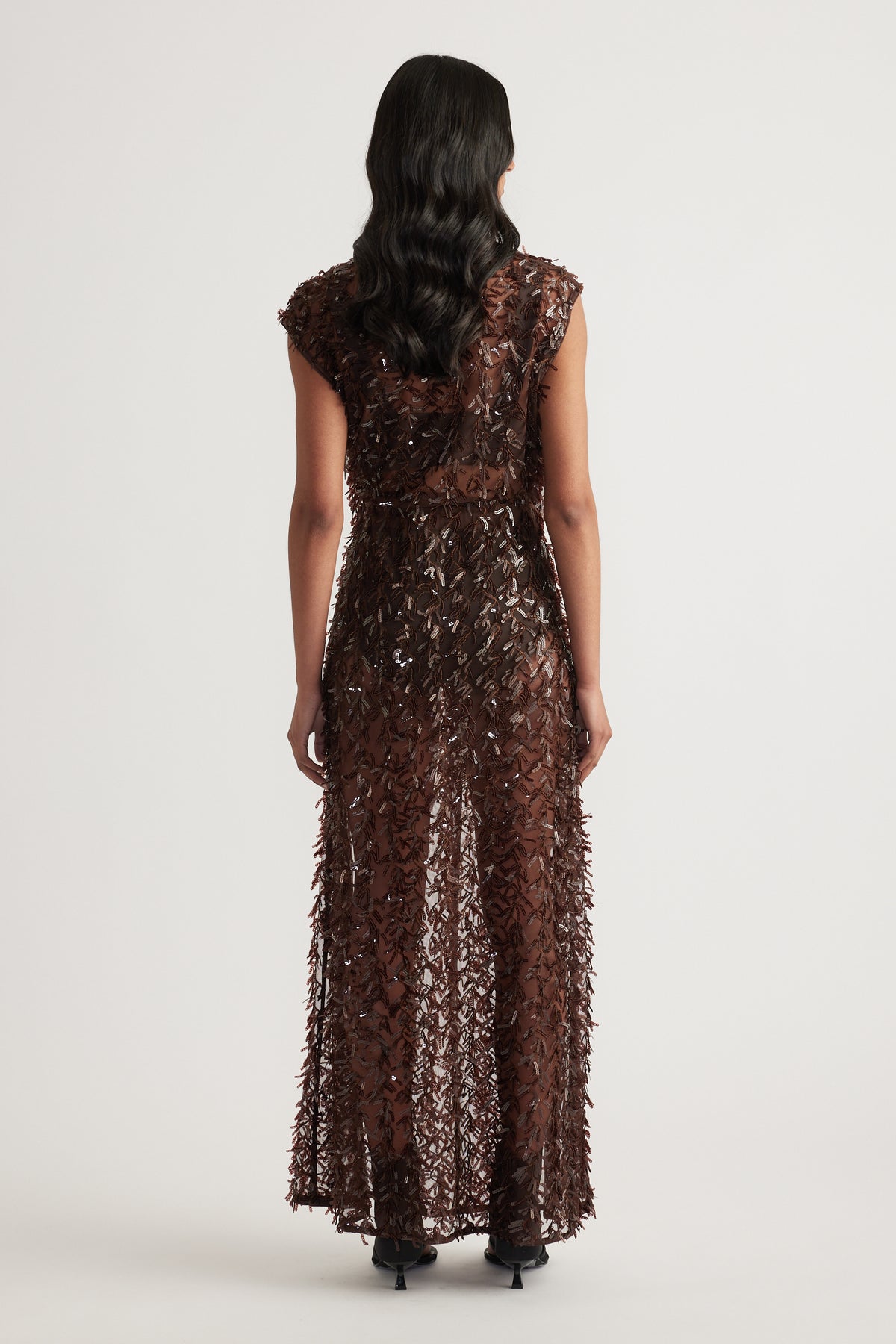 Back view of a woman wearing a brown sequin maxi skirt with a matching top