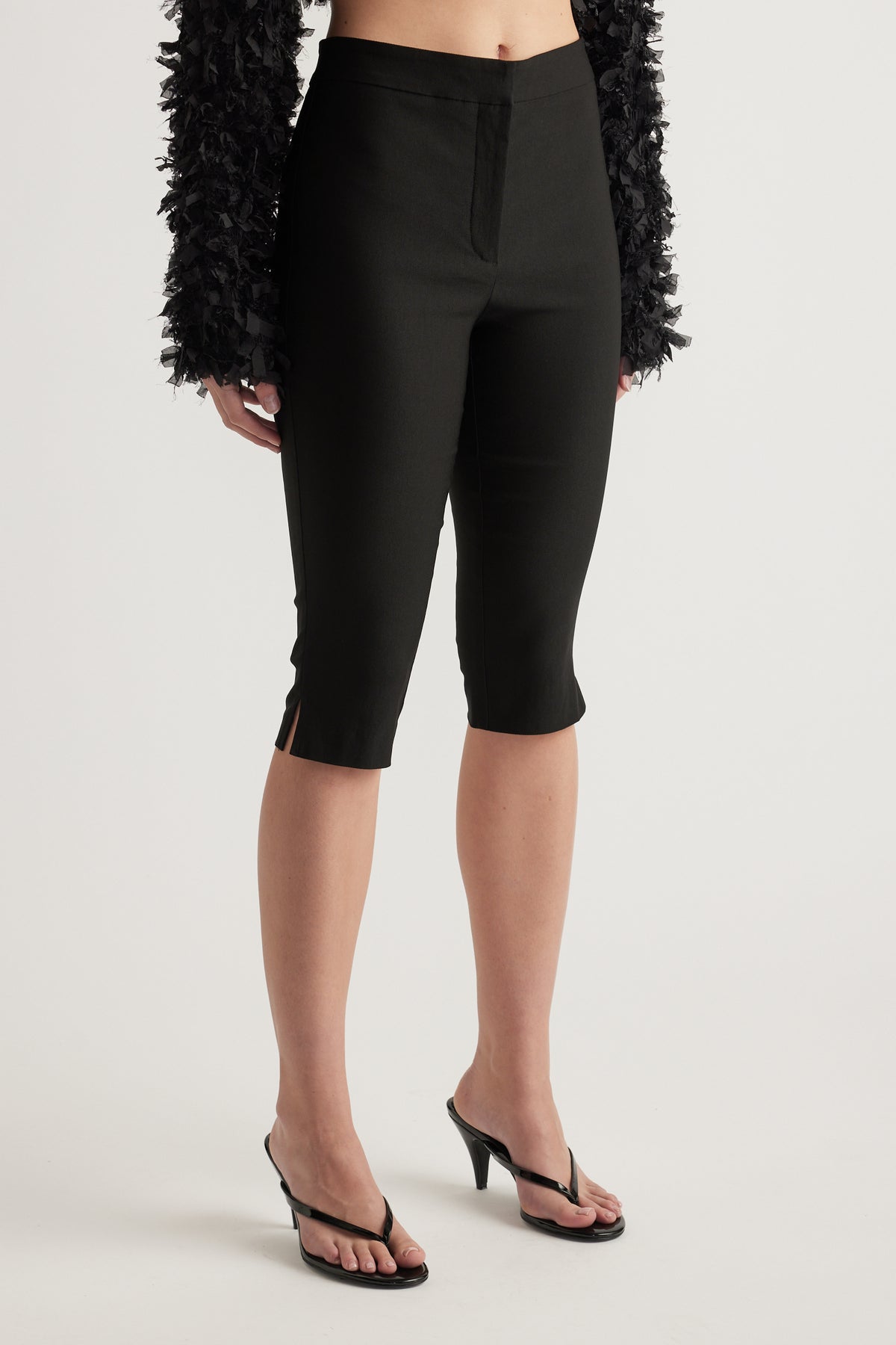 Woman wearing black slim fit capri pants with a mid rise waist and three quarter length hems