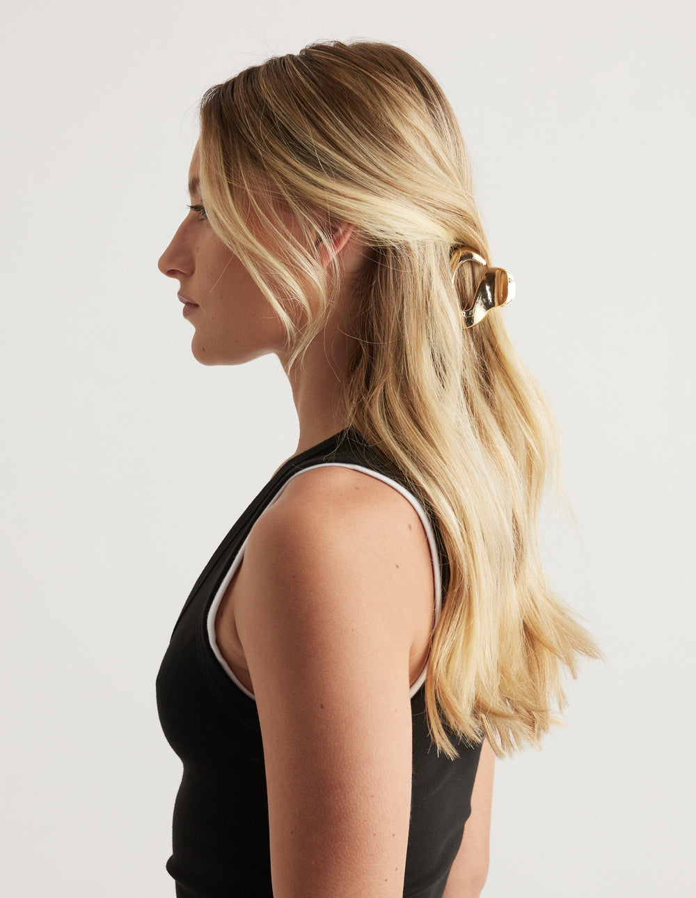 Woman in profile with long blonde hair secured by a small glossy brown oval hair claw clip