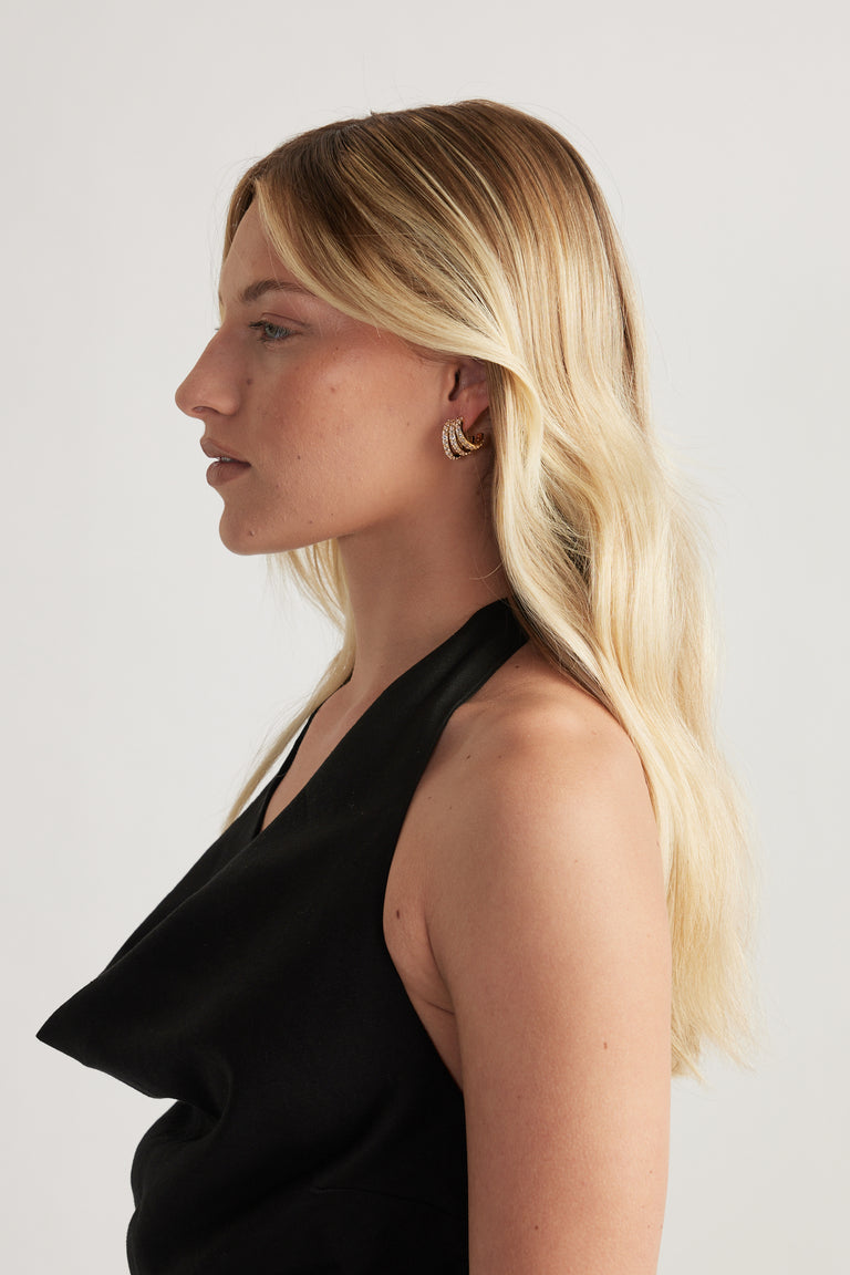 Woman in profile wearing a small gold diamante hoop earring and black halter top
