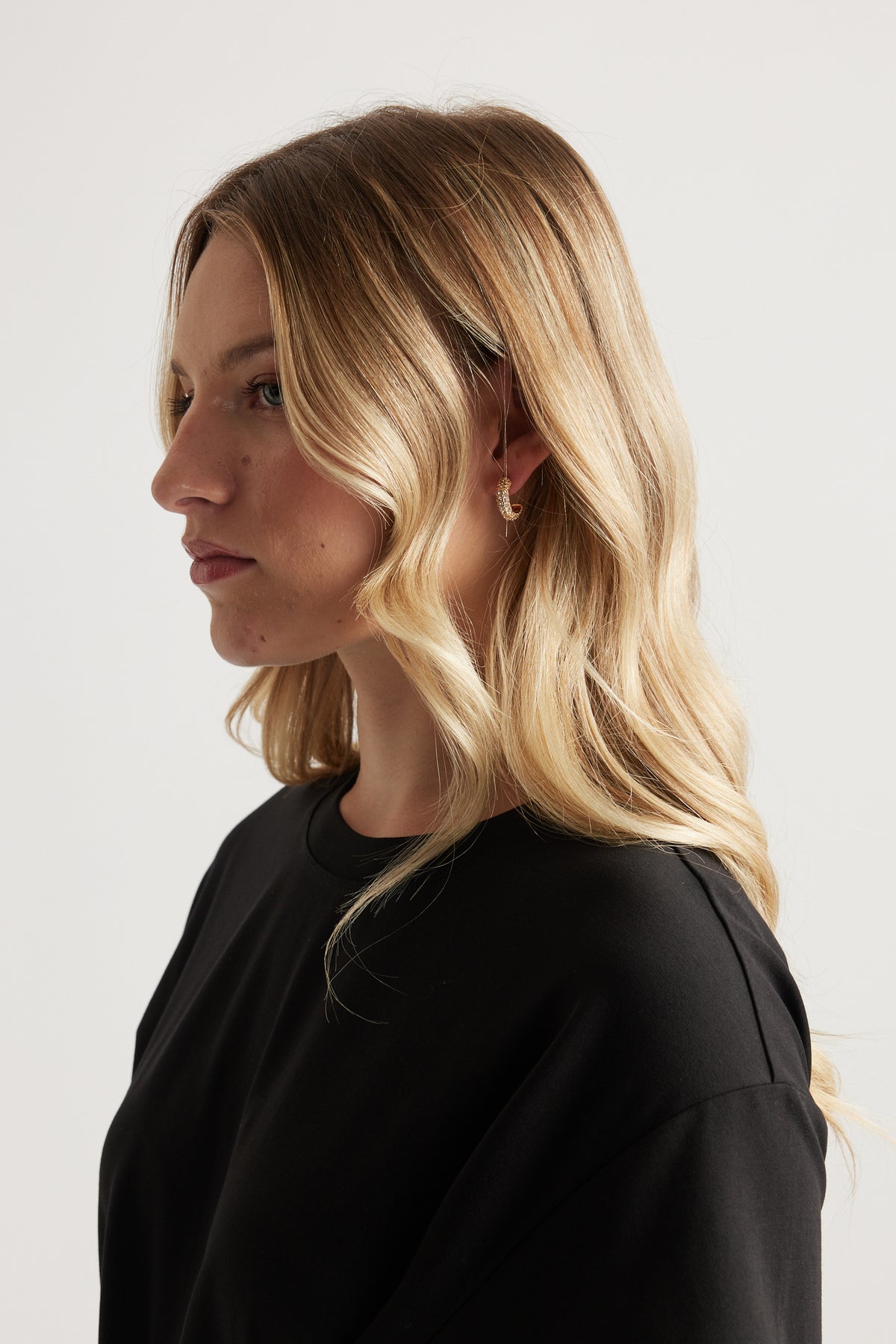 Woman with blonde hair wearing a black top and a small gold hoop earring