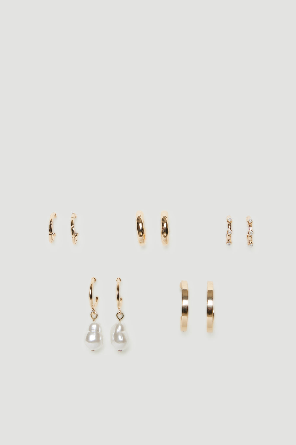 Five pairs of gold tone mini hoop earrings with textured finishes and pearl details