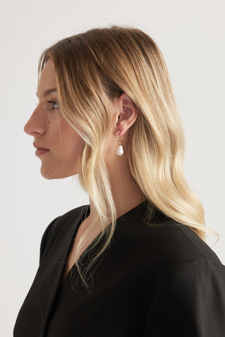Woman in profile wearing a textured mini hoop earring with a pearl drop