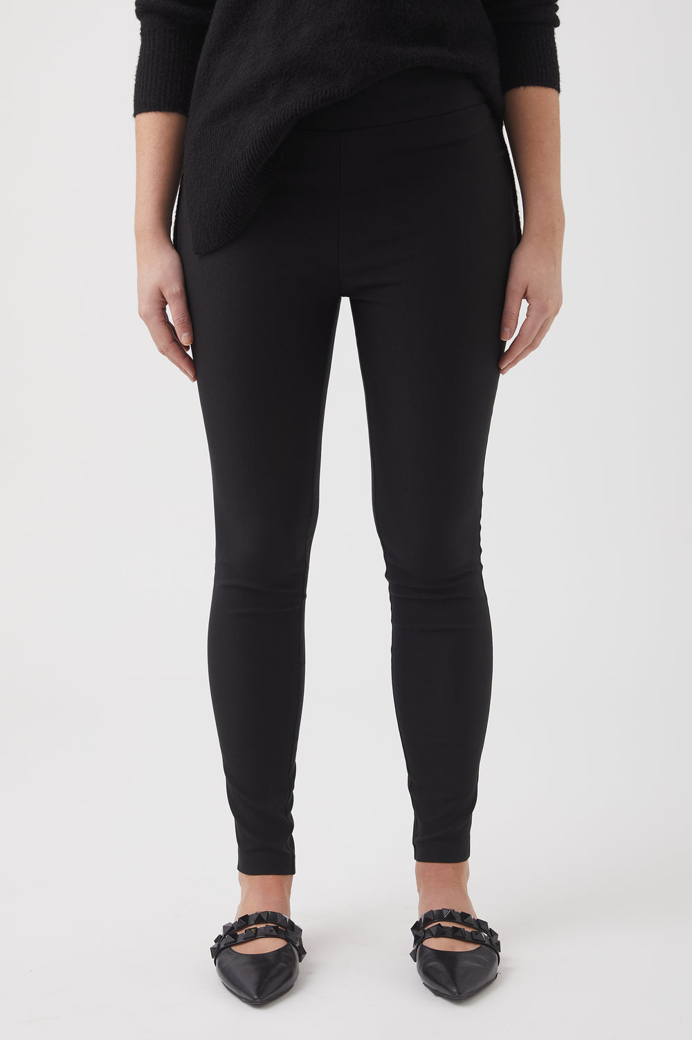 Close-up of woman wearing slim black pants paired with a textured black sweater and pointed flats with embellishments
