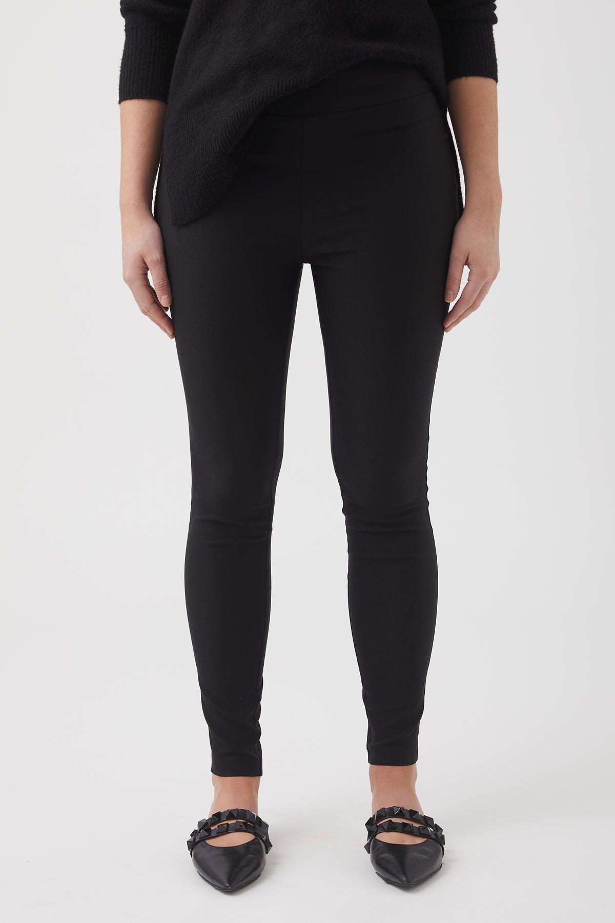 Close-up of woman wearing slim black pants paired with a textured black sweater and pointed flats with embellishments