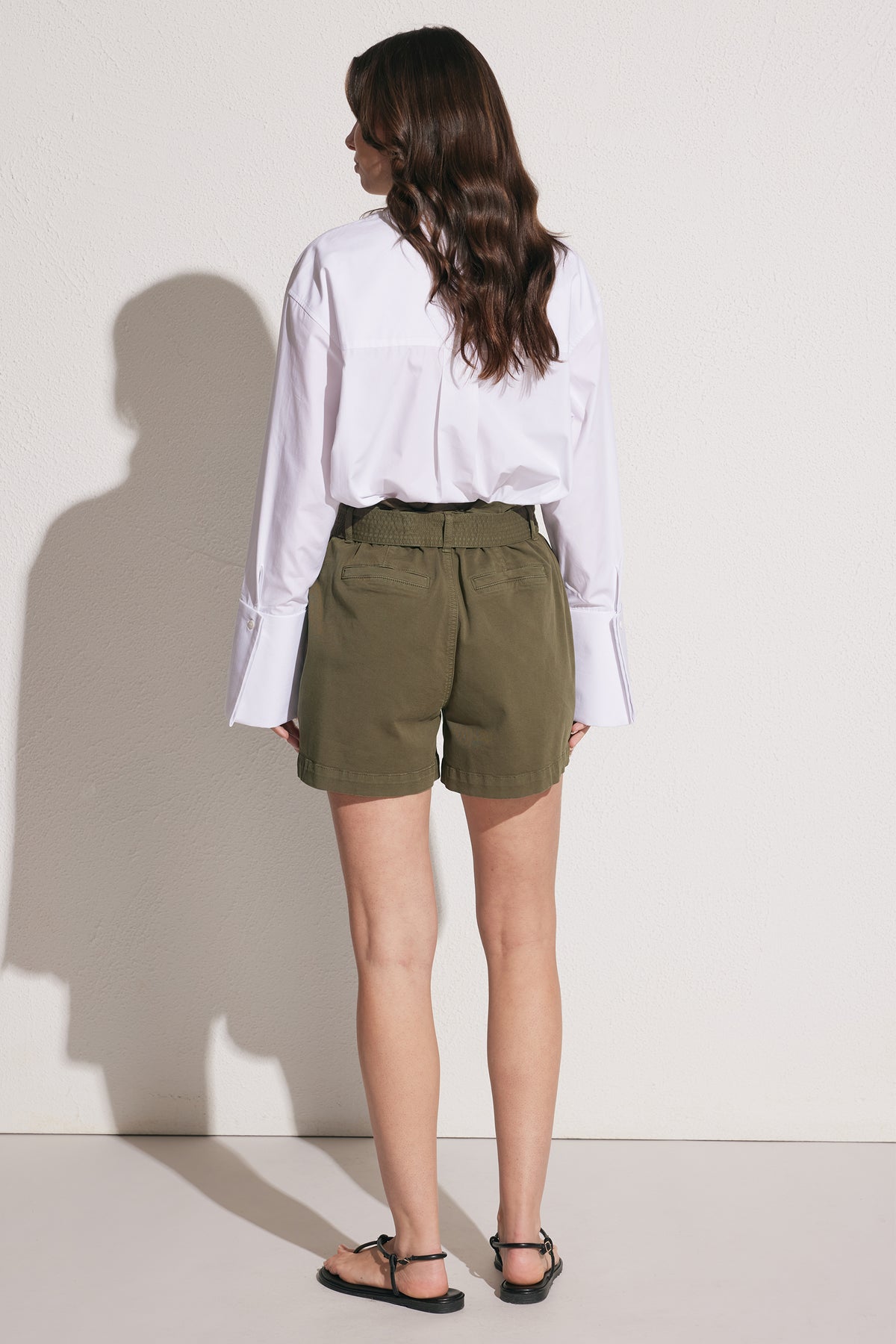 Woman wearing olive cargo shorts with an elastic waist and patch pockets styled with a white shirt and sandals