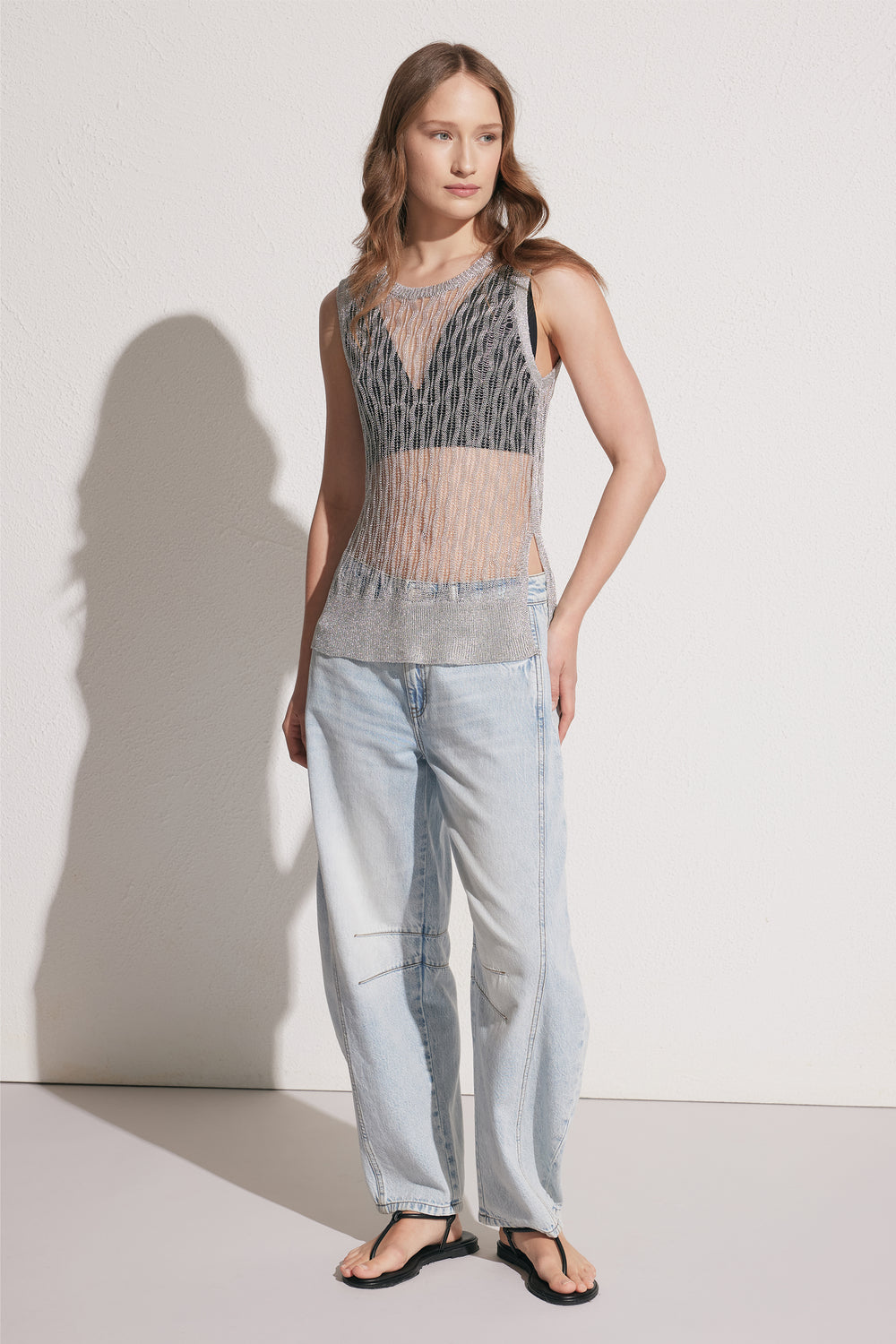 Woman wearing a metallic knit tank with light wash jeans and black sandals