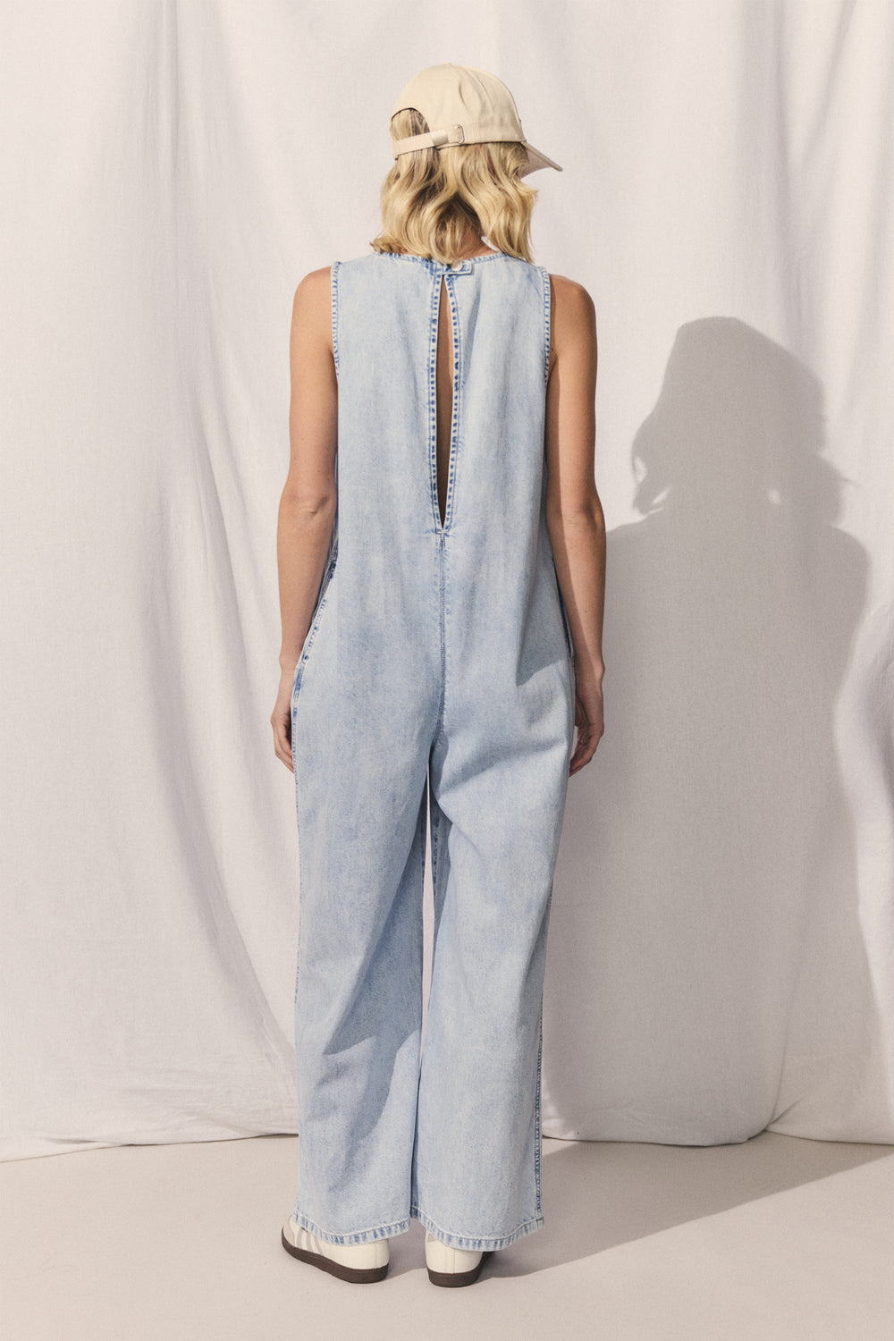 Back view of D-Luxe Palazzo Denim Jumpsuit featuring extended keyhole and straight leg in portrait gallery position 3.