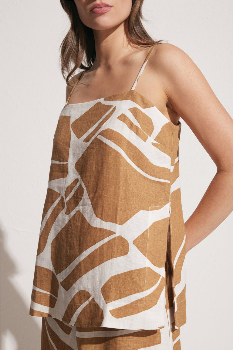Woman wearing a brown and white abstract print linen cami with thin straps, square neckline and side splits