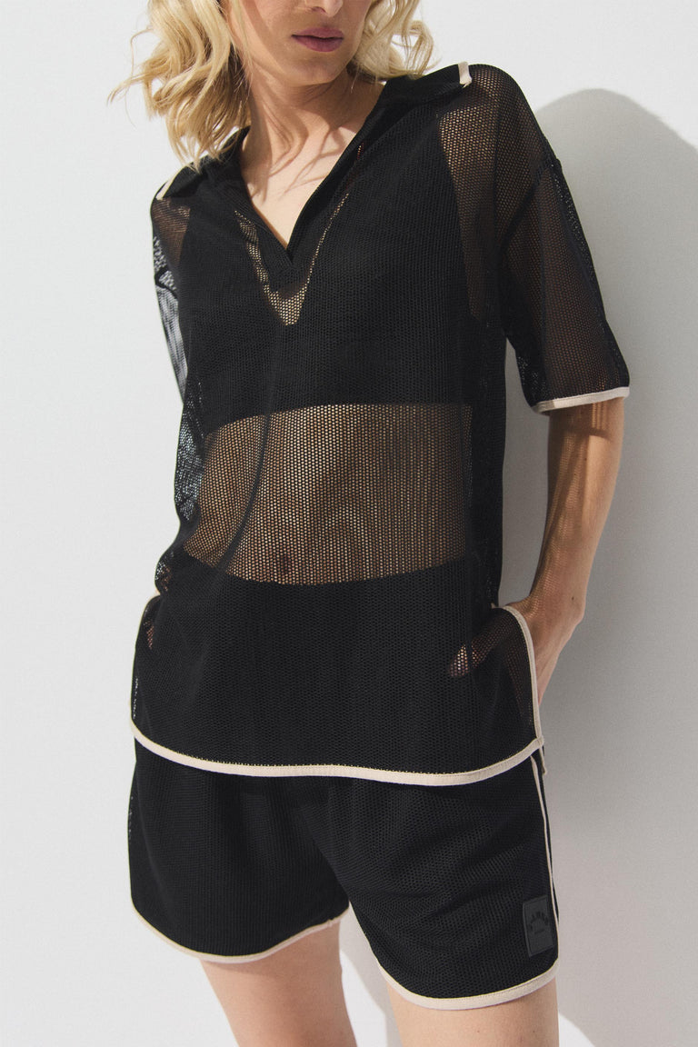 Woman wearing black mesh knit top with white trim and matching shorts, casual relaxed fit with side pockets