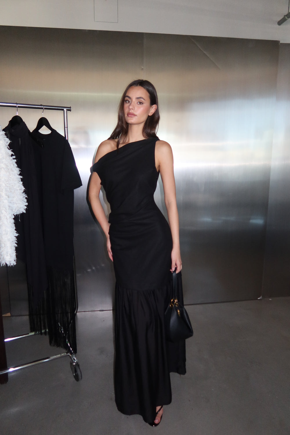 Woman wearing a black draped off shoulder spliced maxi dress
