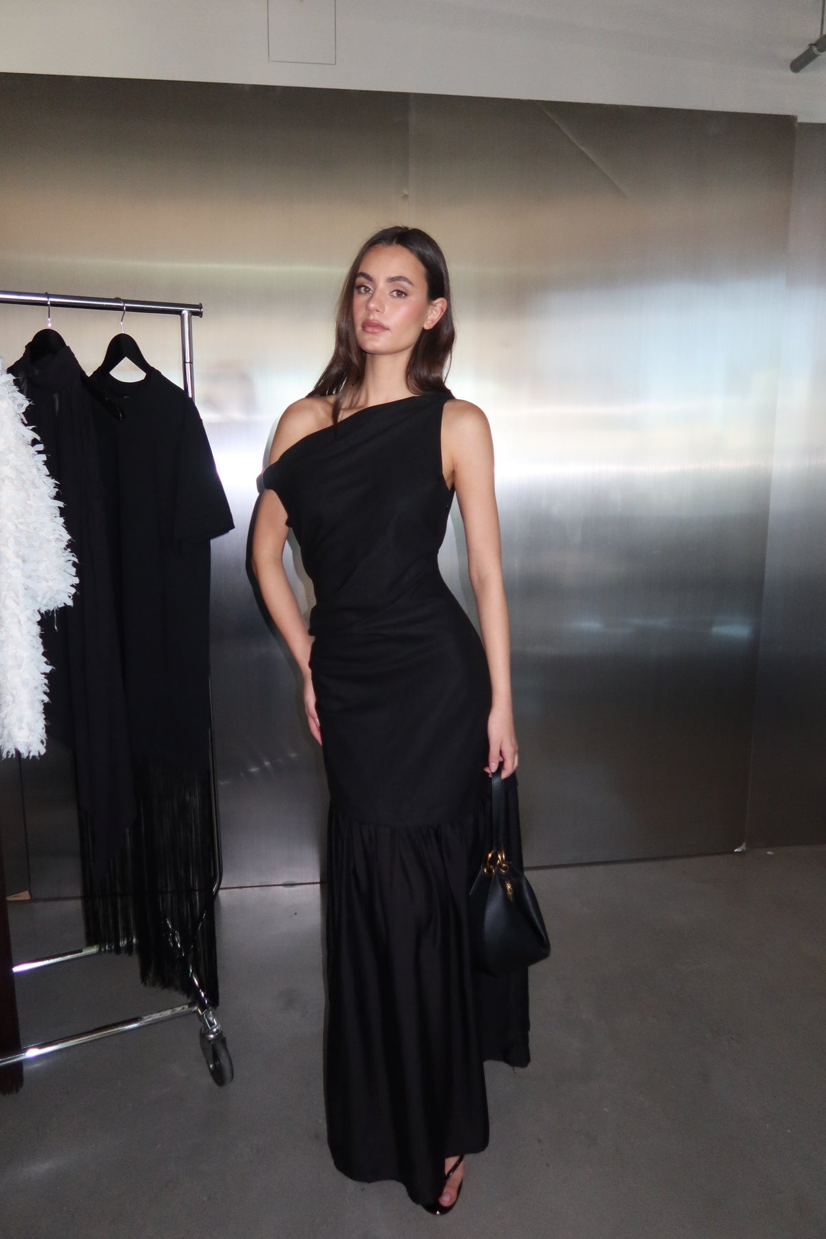 Woman wearing a black draped off shoulder spliced maxi dress
