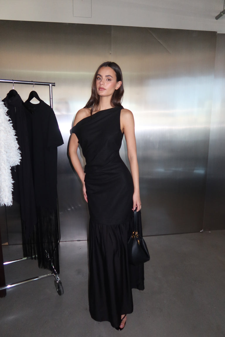 Woman wearing a black draped off shoulder spliced maxi dress