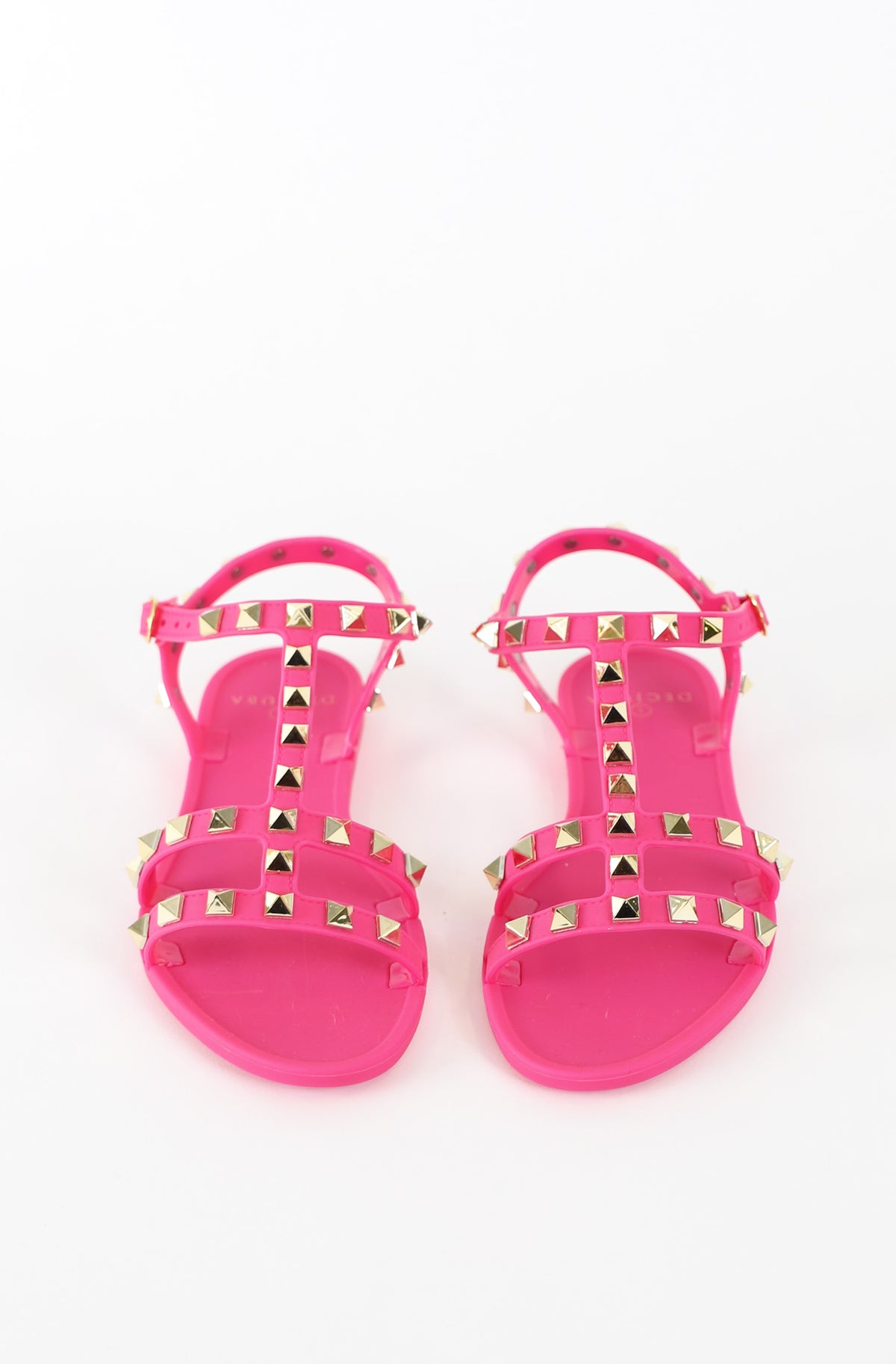 Pair of bright pink girls T bar sandals with pyramid stud detailing and adjustable ankle straps