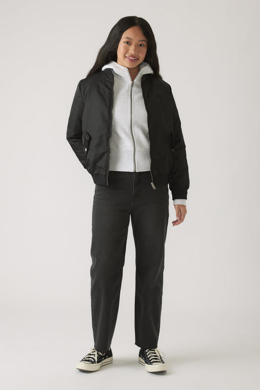 Girl wearing black straight leg jeans paired with a light zip-up hoodie and a black bomber jacket for casual style