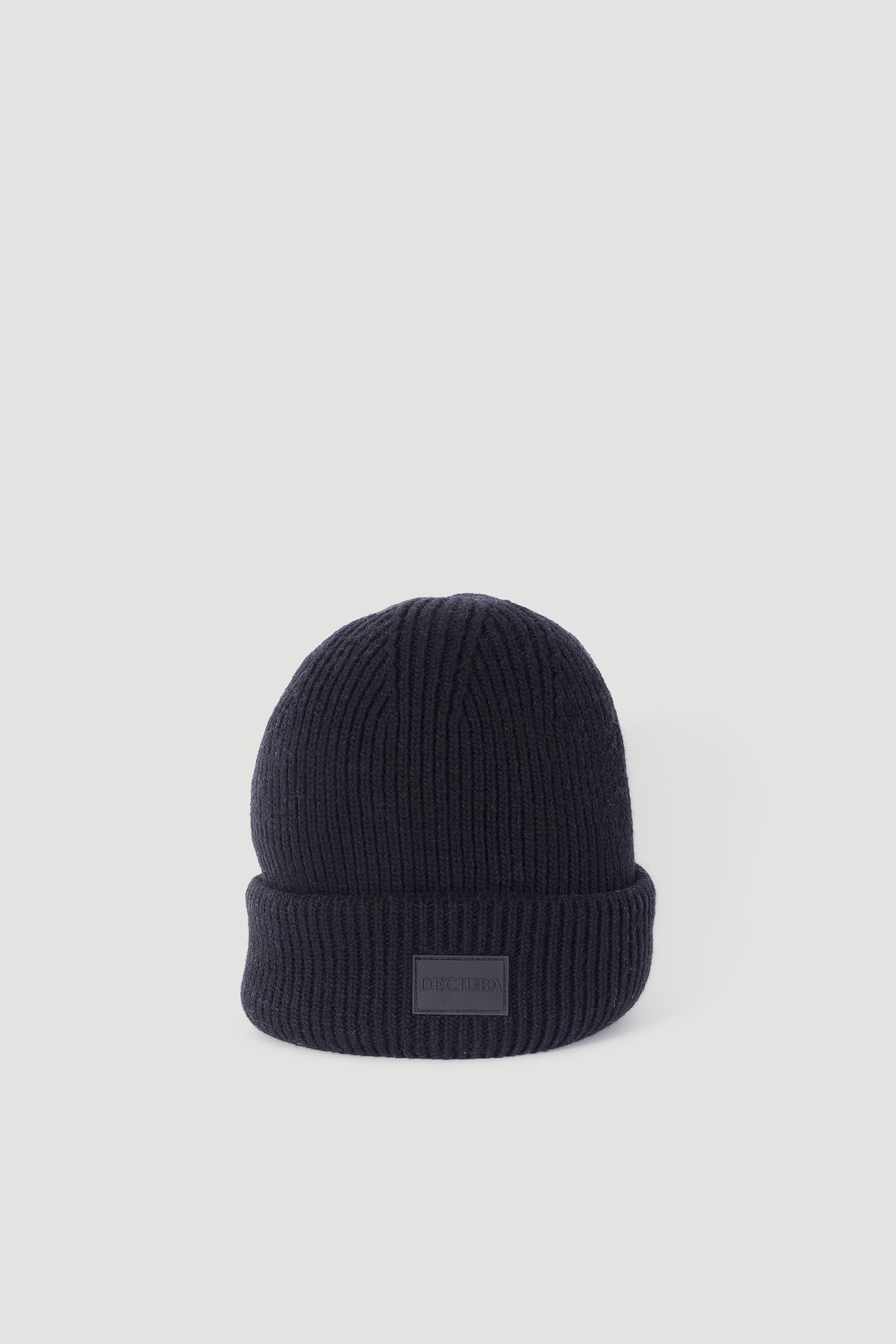 Soft black ribbed knit beanie with folded cuff featuring a tonal patch, designed for everyday minimalist style.
