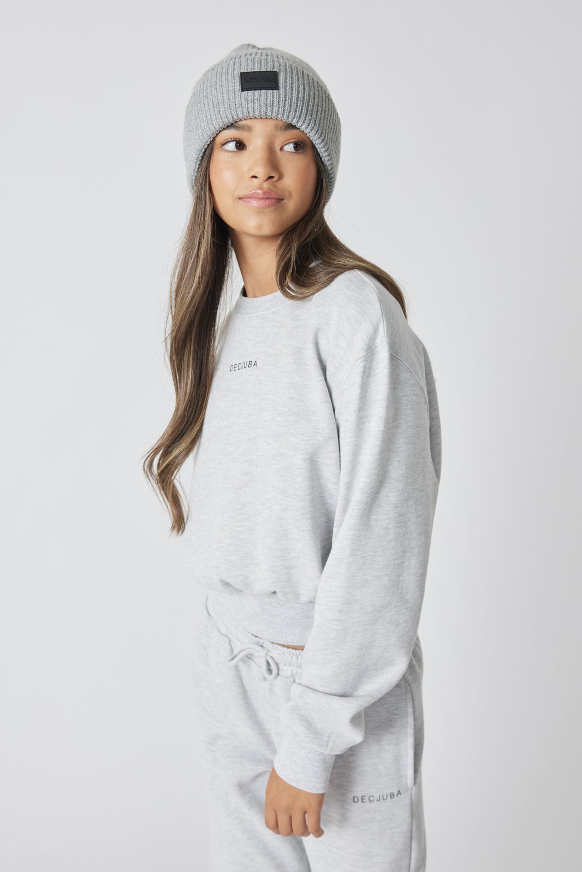 Girl wearing a light grey minimalist beanie paired with a matching casual sweatshirt and joggers set, relaxed pose