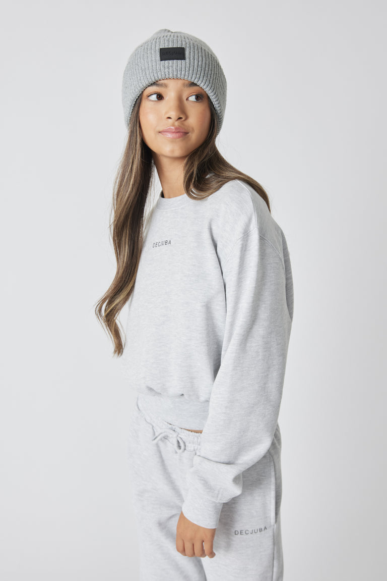 Girl wearing a light grey minimalist beanie paired with a matching casual sweatshirt and joggers set, relaxed pose
