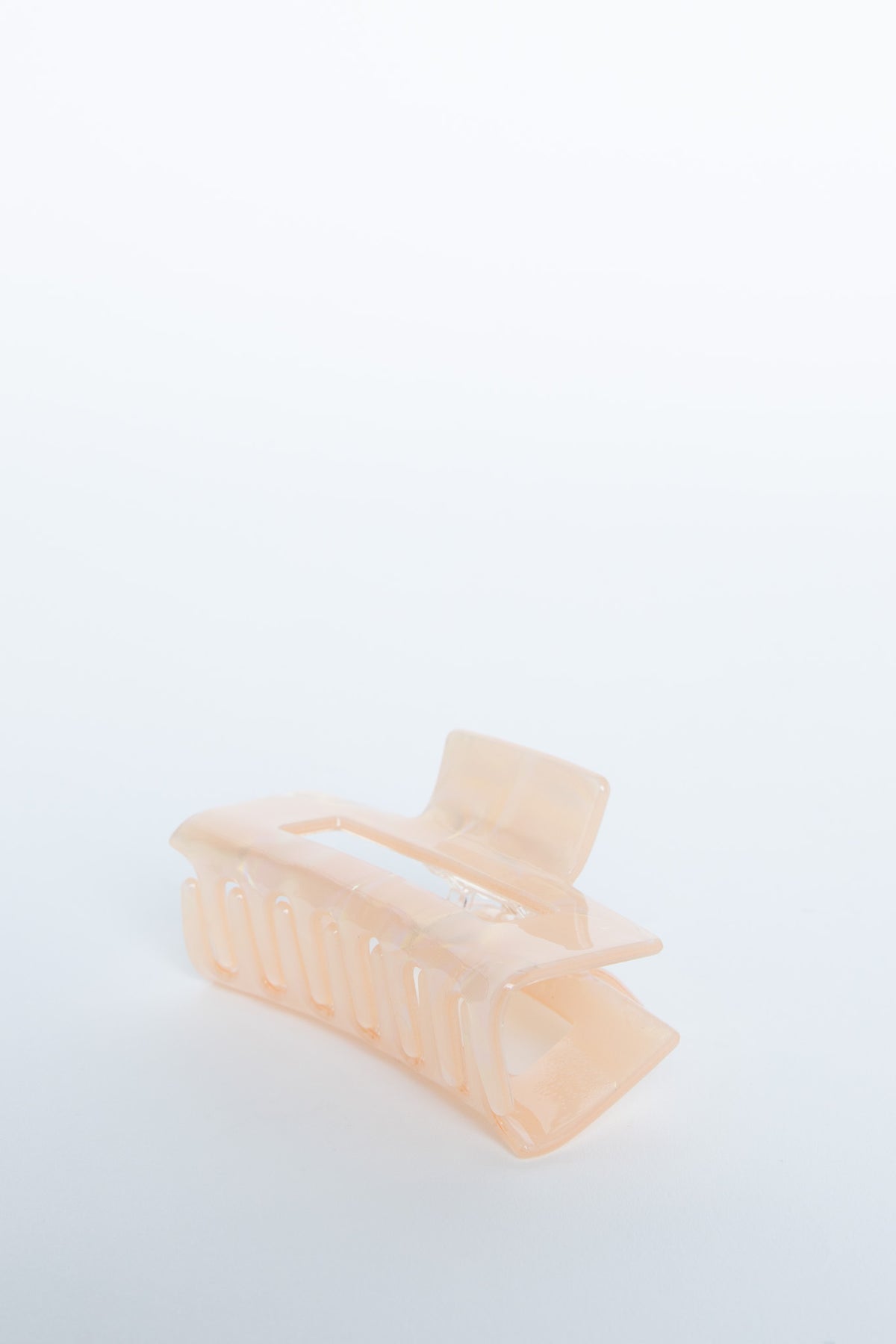 Peach-colored translucent hair claw with a smooth finish, designed for easy hair styling and grip.