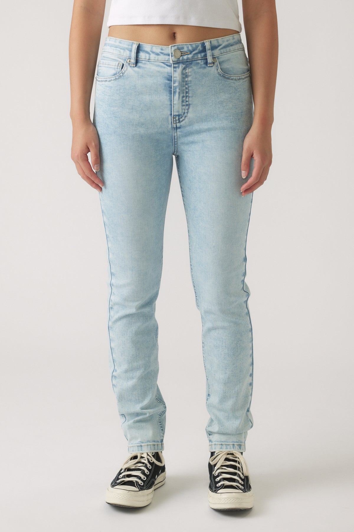 Light wash skinny jeans for girls with a high waist and classic five-pocket design paired with casual sneakers
