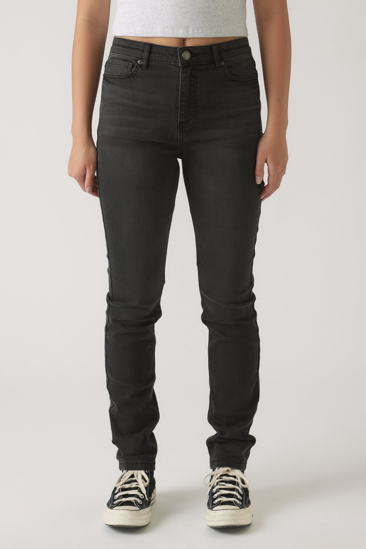Front view of girls wearing black skinny leg denim jeans paired with casual black and white sneakers