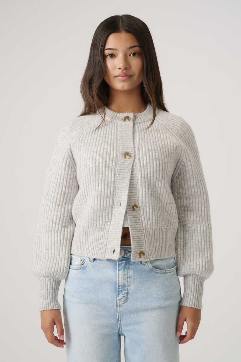 Girl wearing a soft grey ribbed cardigan with button details paired with light blue high-waisted denim jeans