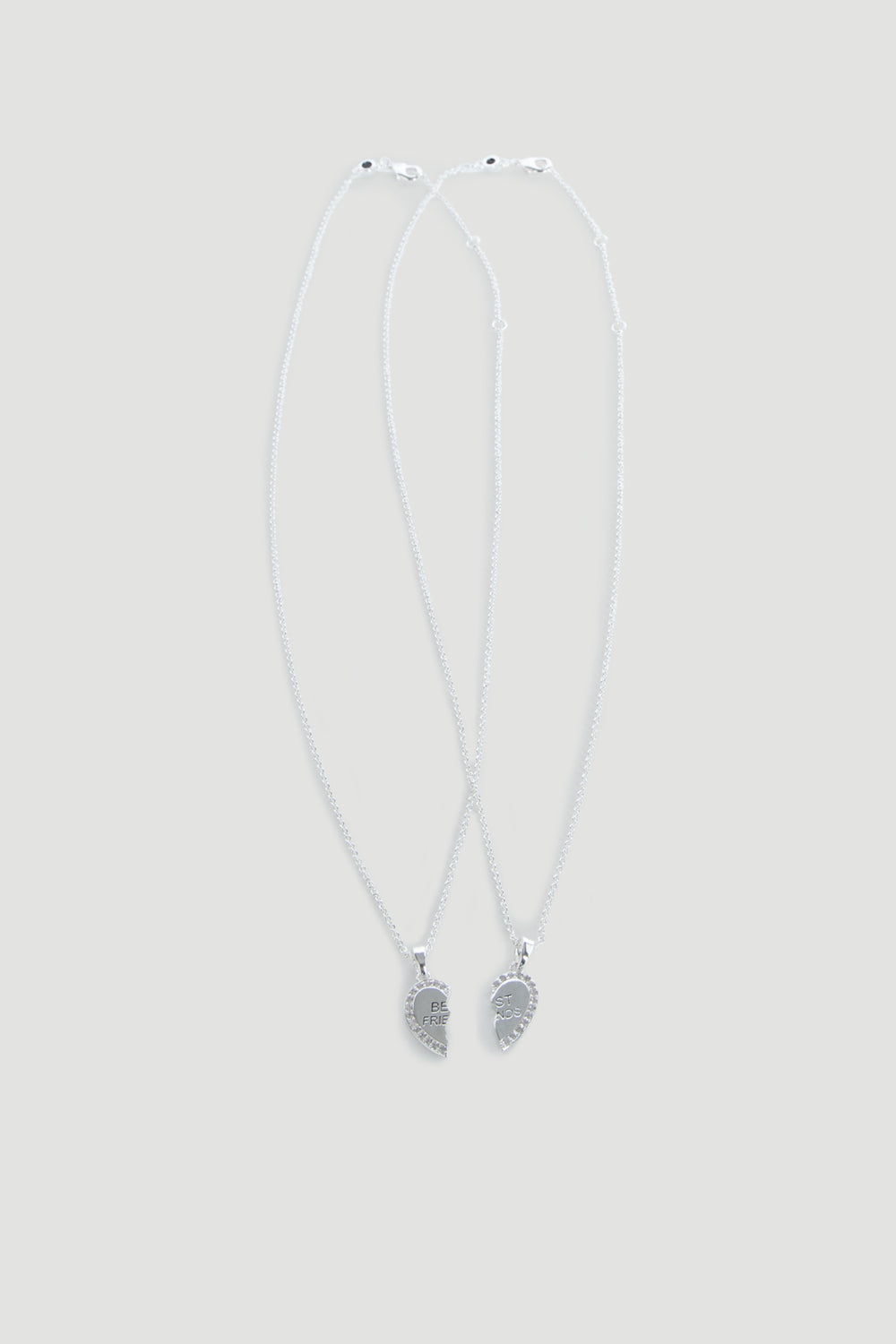 Two delicate silver necklaces each featuring half of a heart pendant engraved with "BFF" for best friends