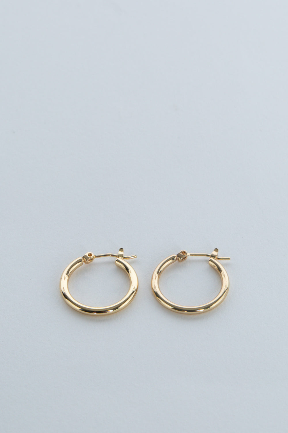 Pair of gold hoop earrings displayed on a pale blue background