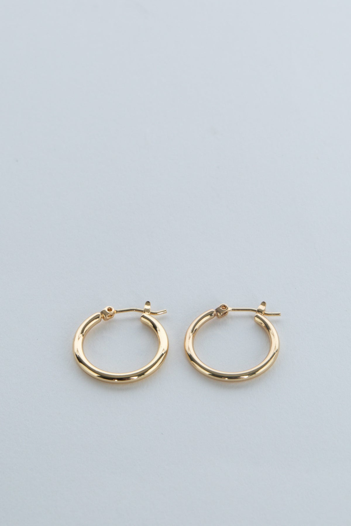 Pair of gold hoop earrings displayed on a pale blue background