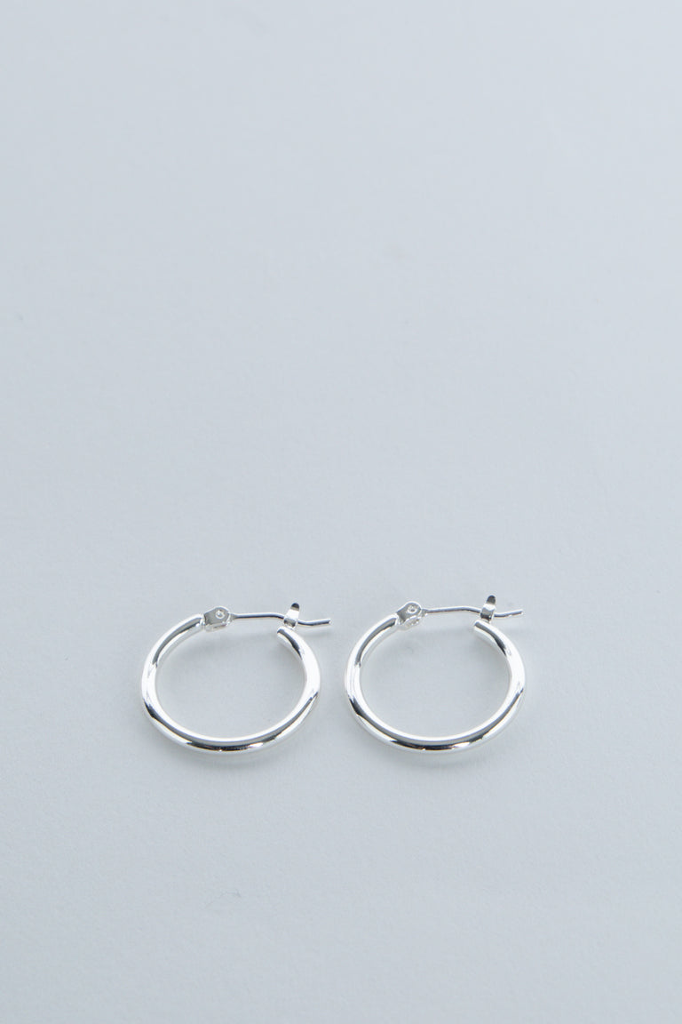 Pair of simple polished silver hoop earrings for girls with secure latch-back closures on soft gray background