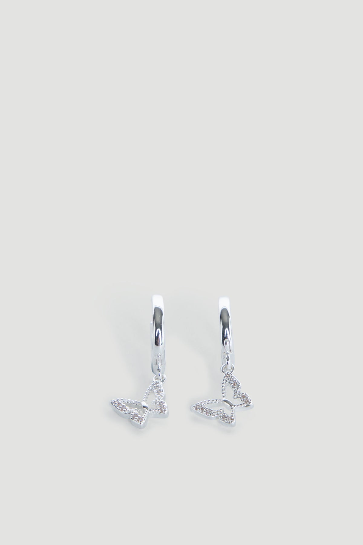 Pair of delicate silver hoop earrings featuring small dangling openwork butterfly charms.