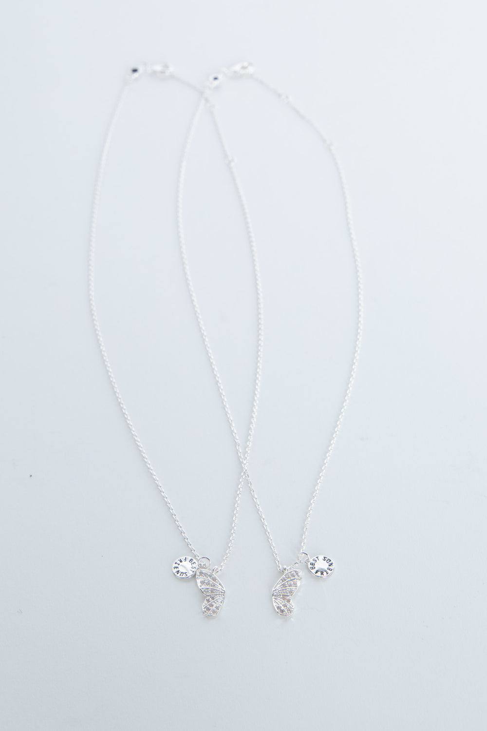 Delicate butterfly pendant necklace with small sparkling charms on a pale background