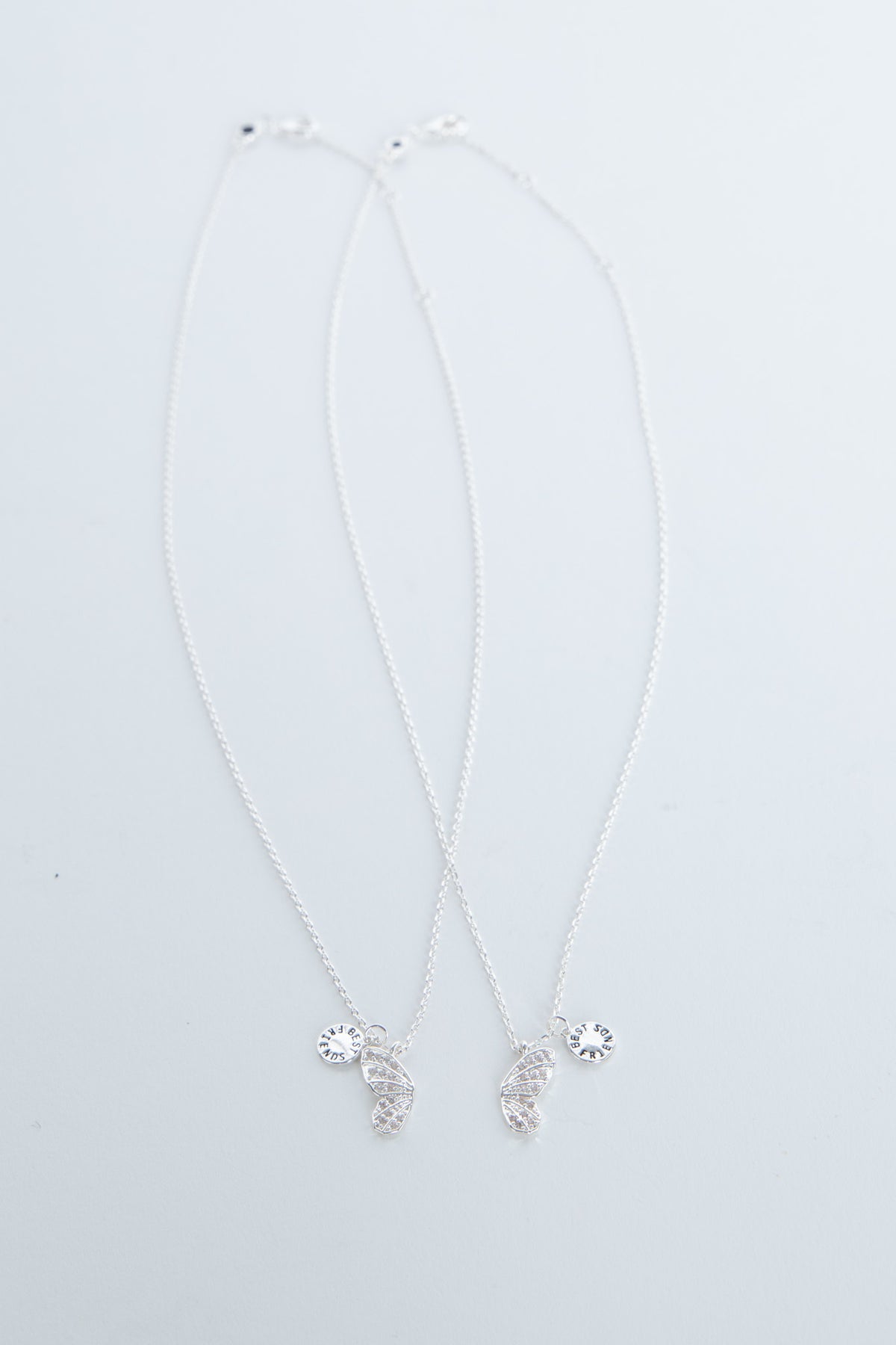 Delicate butterfly pendant necklace with small sparkling charms on a pale background