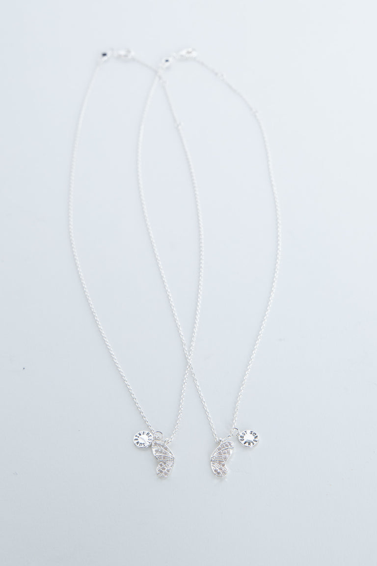 Delicate butterfly pendant necklace with small sparkling charms on a pale background